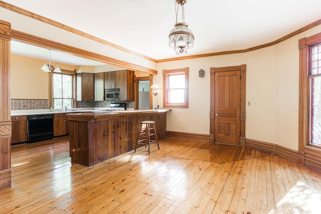 706 Washington Ave, Dixon, IL 61021 - kitchen featuring black dishwasher, stainless steel microwave, a chandelier, light wood-style flooring, and backsplash