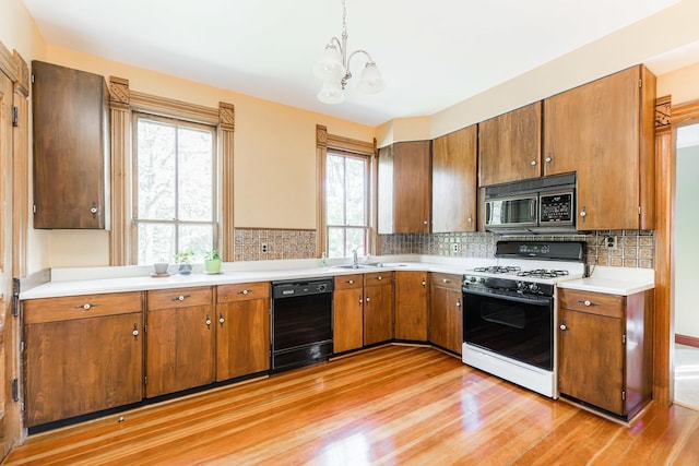 706 Washington Ave, Dixon, IL 61021 - kitchen with black dishwasher, range with gas cooktop, light wood-style floors, a chandelier, and brown cabinets