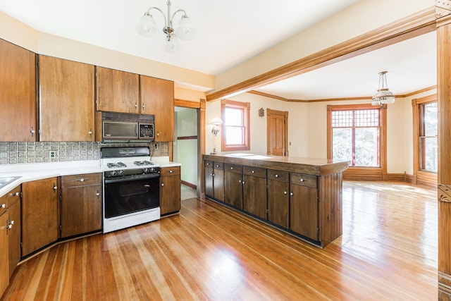 706 Washington Ave, Dixon, IL 61021 - kitchen featuring a chandelier, black microwave, range with gas stovetop, light wood-type flooring, and plenty of natural light