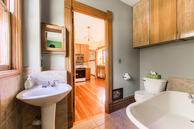 706 Washington Ave, Dixon, IL 61021 - bathroom featuring a tub to relax in, a sink, toilet, tile patterned flooring, and a chandelier
