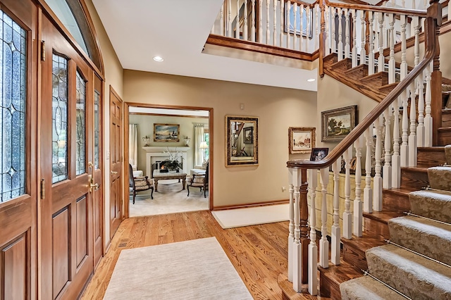 2 Hampton Ct, Burr Ridge, IL 60527 - foyer entrance featuring a warm lit fireplace, healthy amount of natural light, light wood-type flooring, stairway, and a towering ceiling
