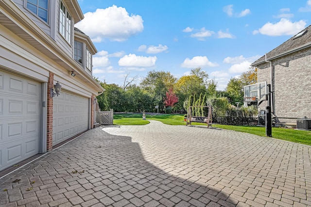 2 Hampton Ct, Burr Ridge, IL 60527 - garage with decorative driveway, central AC unit, and view of wooded area
