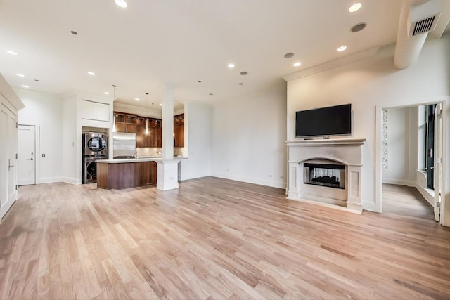 333 W Hubbard St Unit 704, Chicago, IL 60654 - unfurnished living room with estacked washer and dryer, light wood-type flooring, a fireplace, baseboards, and recessed lighting
