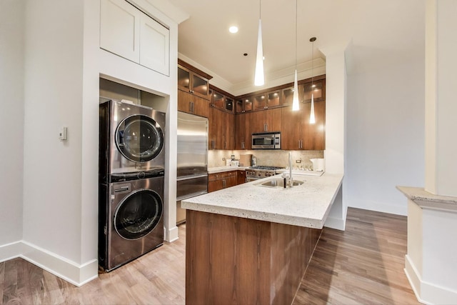 333 W Hubbard St Unit 704, Chicago, IL 60654 - kitchen featuring stainless steel appliances, estacked washer and dryer, a peninsula, and light wood-style flooring