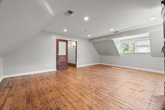 additional living space featuring light wood-style floors, lofted ceiling, baseboards, and recessed lighting