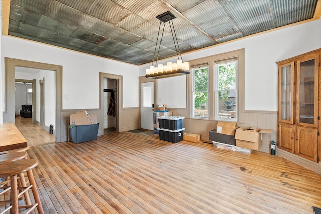 dining area with wood-type flooring, a wainscoted wall, and a chandelier