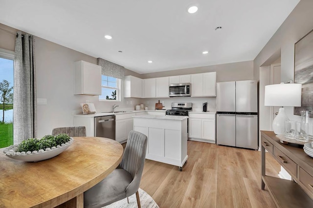5010 Linden Rd, Mount Pleasant, WI 53403 - kitchen with stainless steel appliances, a sink, white cabinetry, light wood-type flooring, and a kitchen island