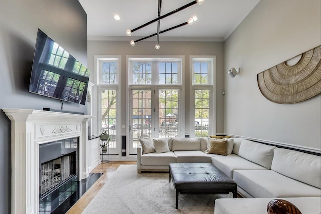 3506 N Southport Ave Unit 1N, Chicago, IL 60657 - living room featuring ornamental molding, a fireplace with flush hearth, light wood-type flooring, a high ceiling, and a chandelier