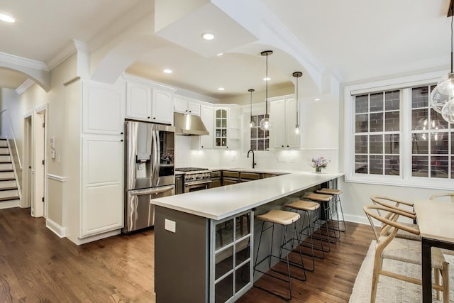 3506 N Southport Ave Unit 1N, Chicago, IL 60657 - kitchen featuring appliances with stainless steel finishes, arched walkways, crown molding, a peninsula, and a breakfast bar area