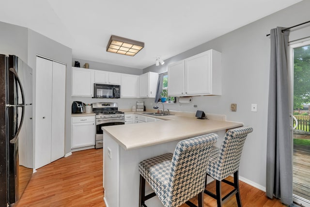 1604 Heritage Pointe Ct, Plainfield, IL 60586 - kitchen with black appliances, a kitchen bar, light wood finished floors, a peninsula, and a sink