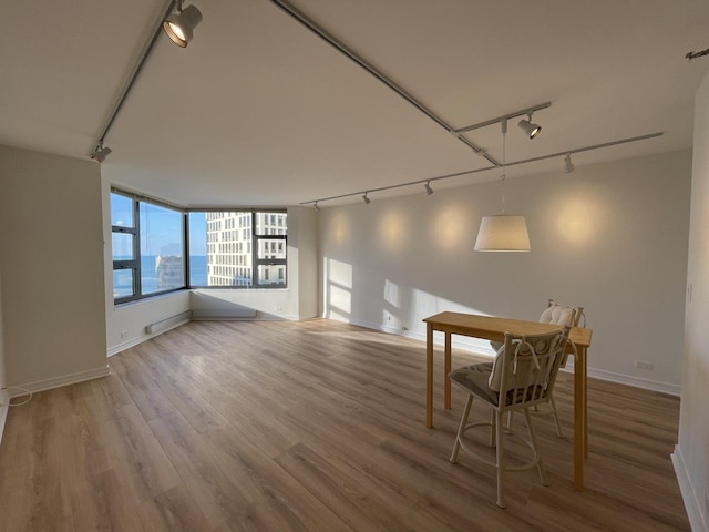 dining area featuring track lighting, wood finished floors, and baseboards