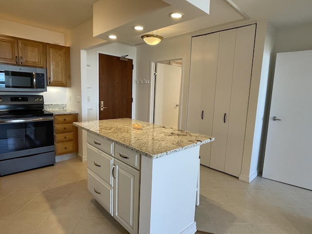 kitchen featuring appliances with stainless steel finishes, light tile patterned floors, light stone counters, brown cabinetry, and recessed lighting