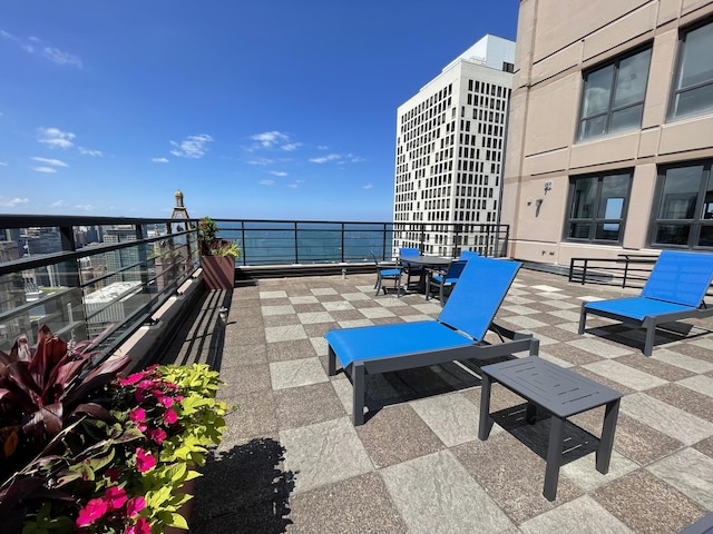 view of patio / terrace with a water view, a balcony, and outdoor dining space