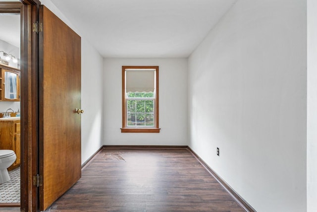 unfurnished bedroom with a sink, wood finished floors, and baseboards