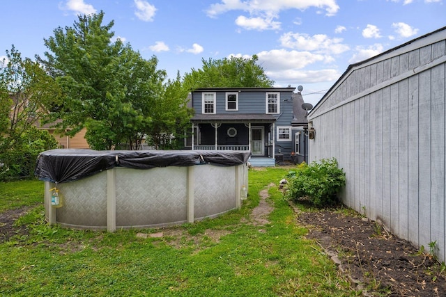 back of property with a covered pool and a yard