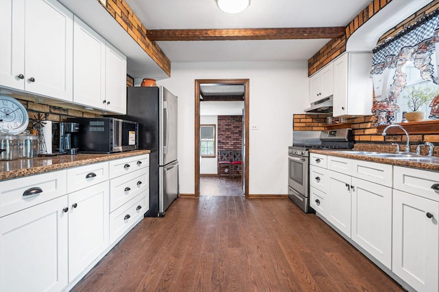 kitchen with stainless steel appliances, under cabinet range hood, a sink, beamed ceiling, and backsplash
