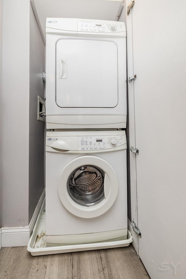 21 W Chestnut St Unit 907, Chicago, IL 60610 - laundry area featuring stacked washer and clothes dryer, wood finished floors, and baseboards