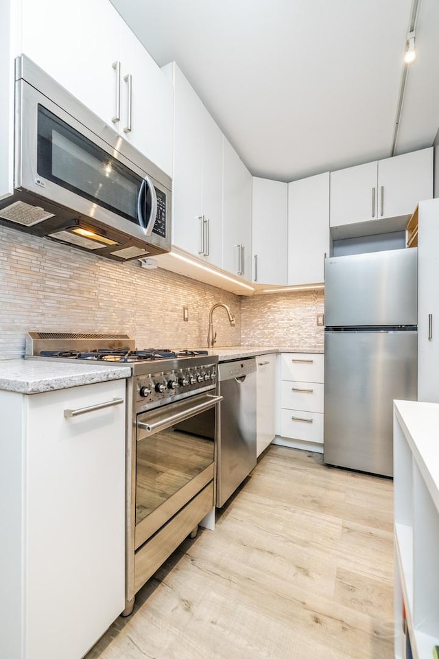 21 W Chestnut St Unit 907, Chicago, IL 60610 - kitchen with appliances with stainless steel finishes, light wood-style floors, white cabinetry, and backsplash