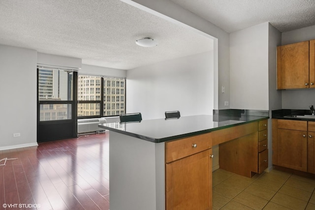 30 E Huron St Unit 2708, Chicago, IL 60611 - kitchen with a peninsula, a textured ceiling, brown cabinetry, a sink, and baseboards