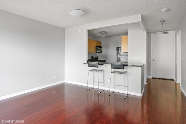 30 E Huron St Unit 2708, Chicago, IL 60611 - kitchen with appliances with stainless steel finishes, dark countertops, dark wood finished floors, a textured ceiling, and baseboards