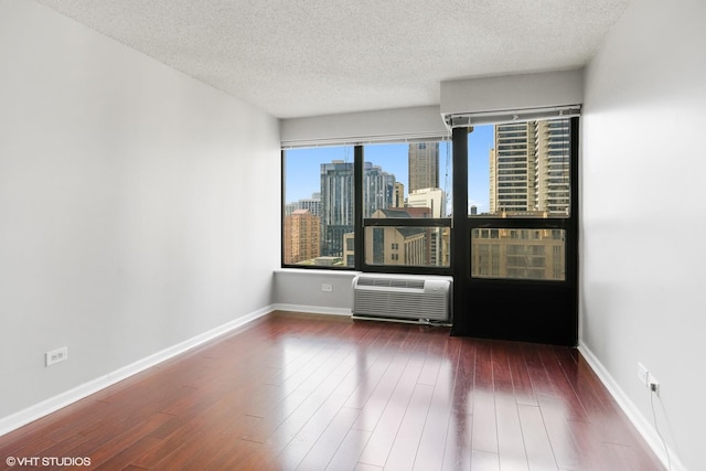 30 E Huron St Unit 2708, Chicago, IL 60611 - empty room with a textured ceiling, a skyline view, baseboards, an AC wall unit, and wood finished floors