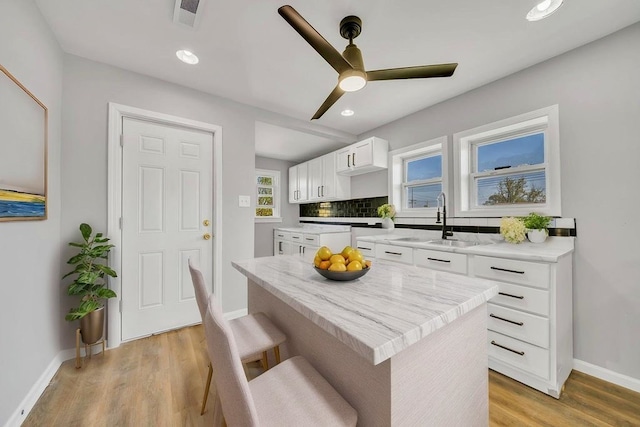 14631 Vincennes Rd, Harvey, IL 60426 - kitchen with white cabinetry, baseboards, a sink, ceiling fan, and a kitchen island