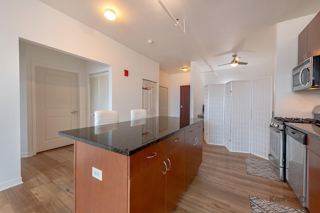 437 W Division St Unit 505, Chicago, IL 60610 - kitchen featuring stainless steel appliances, light wood-type flooring, a center island, ceiling fan, and dark stone counters