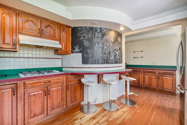 22614 S Joseph Ave, Channahon, IL 60410 - kitchen with under cabinet range hood, freestanding refrigerator, brown cabinetry, and light wood-style floors