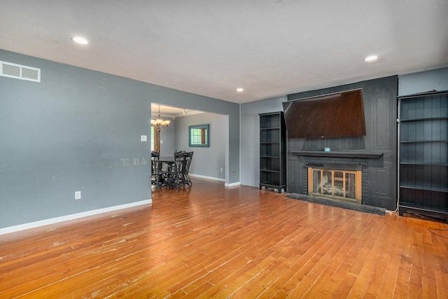 22614 S Joseph Ave, Channahon, IL 60410 - unfurnished living room featuring a chandelier, a brick fireplace, wood finished floors, built in shelves, and recessed lighting
