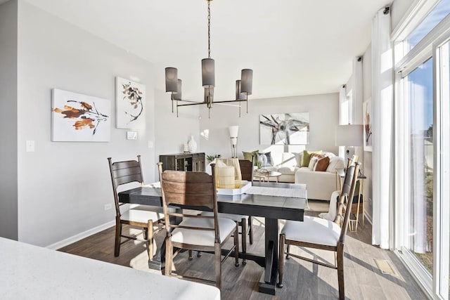 dining space with wood finished floors, a chandelier, and baseboards