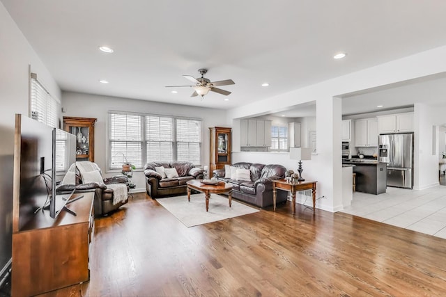 living area with a ceiling fan, healthy amount of natural light, recessed lighting, light wood-style flooring, and baseboards