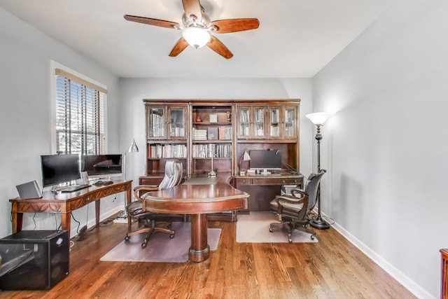 office area with a ceiling fan, wood finished floors, and baseboards