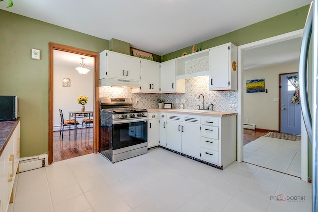 kitchen featuring stainless steel range with gas stovetop, under cabinet range hood, a sink, a baseboard heating unit, and decorative backsplash