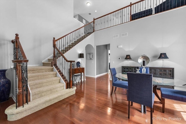 3879 Seigle Dr, Elgin, IL 60124 - dining room featuring arched walkways, hardwood / wood-style floors, stairs, a high ceiling, and baseboards