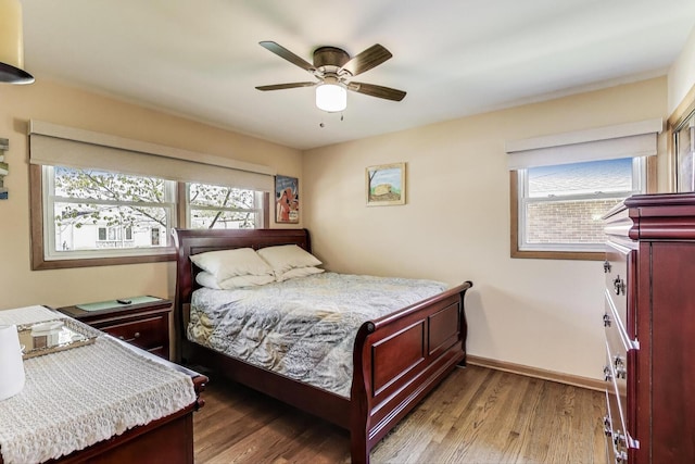 bedroom featuring multiple windows, wood finished floors, baseboards, and ceiling fan