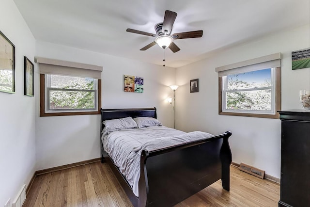 bedroom with multiple windows, wood finished floors, baseboards, and ceiling fan