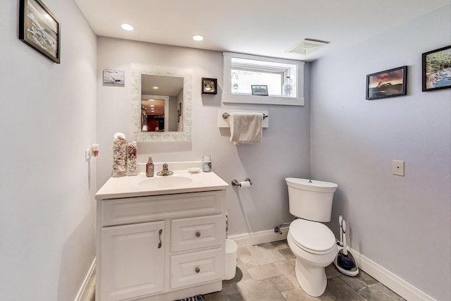 bathroom with toilet, baseboards, and vanity