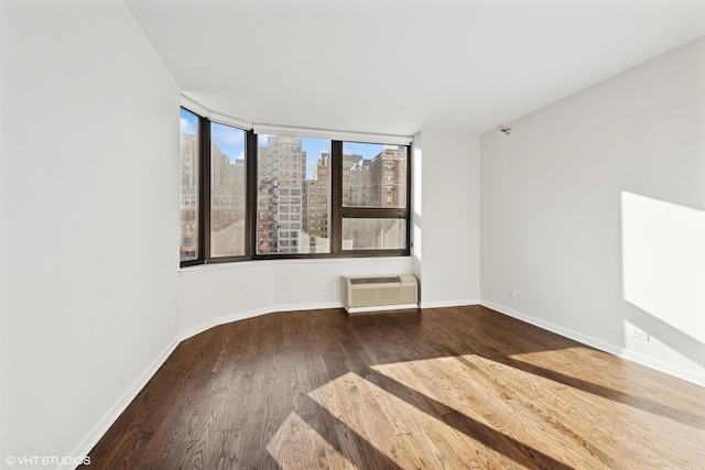 221 E Walton Pl Unit 10B, Chicago, IL 60611 - empty room featuring a wall mounted AC, baseboards, wood finished floors, and a skyline view