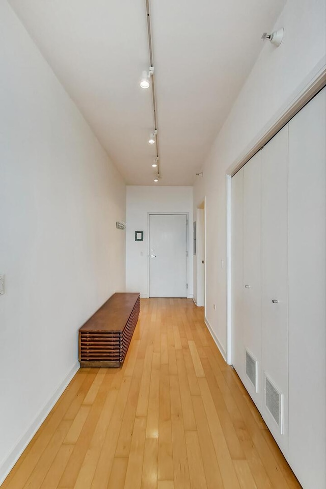 hallway with rail lighting, light wood-type flooring, and baseboards