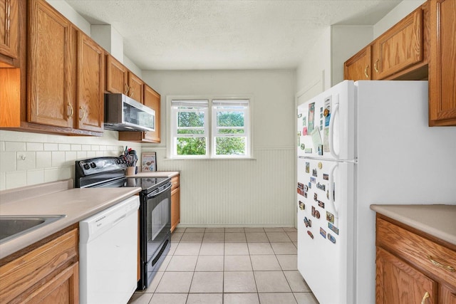608 Hessel Blvd, Champaign, IL 61820 - kitchen featuring white appliances, brown cabinetry, light countertops, wainscoting, and light tile patterned floors