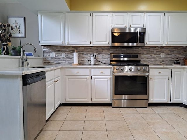 kitchen featuring appliances with stainless steel finishes, a sink, light countertops, a peninsula, and light tile patterned floors