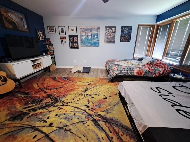 bedroom featuring wood finished floors, baseboards, and a ceiling fan