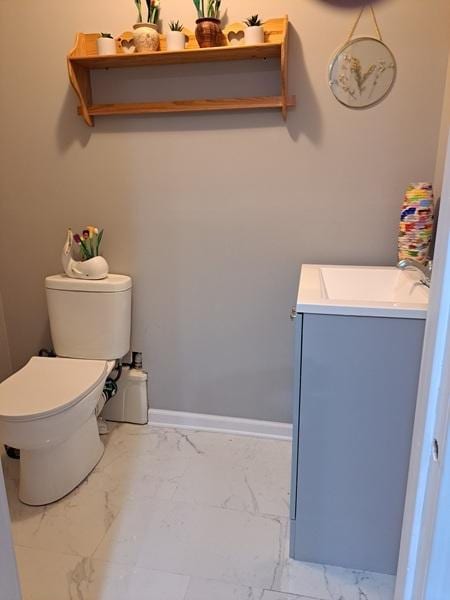 bathroom featuring marble finish flooring, toilet, vanity, and baseboards