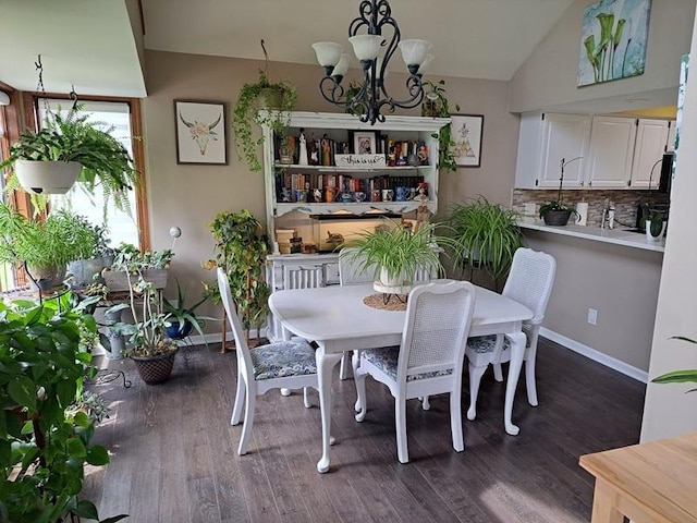 dining room featuring a chandelier, dark wood-style flooring, baseboards, and lofted ceiling