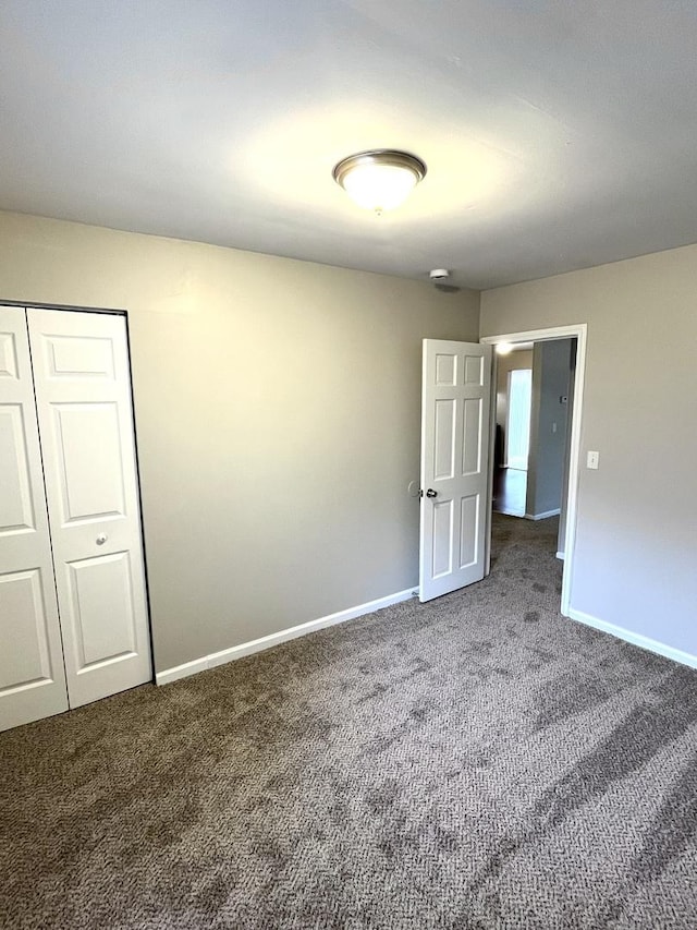 unfurnished bedroom with carpet floors, baseboards, and a closet
