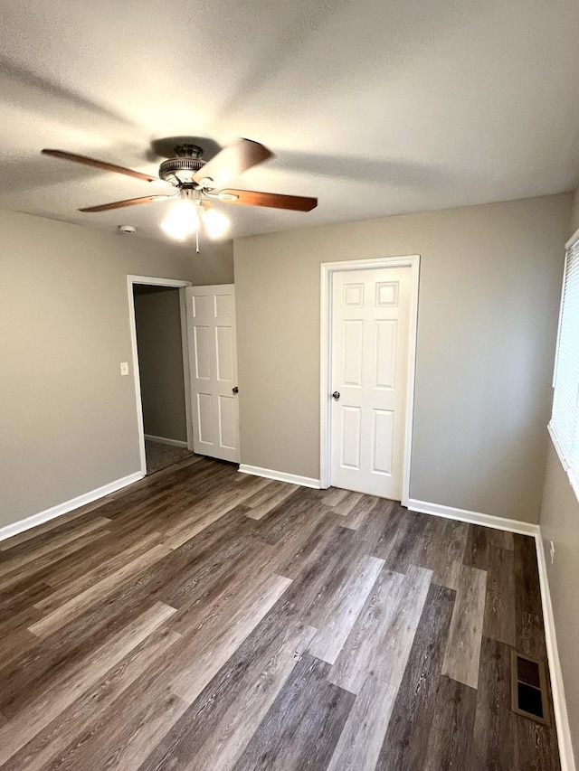 unfurnished bedroom featuring baseboards, dark wood-style flooring, and ceiling fan
