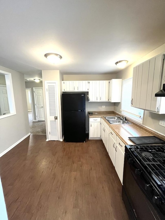 kitchen with black appliances, a sink, dark wood-style flooring, under cabinet range hood, and white cabinetry