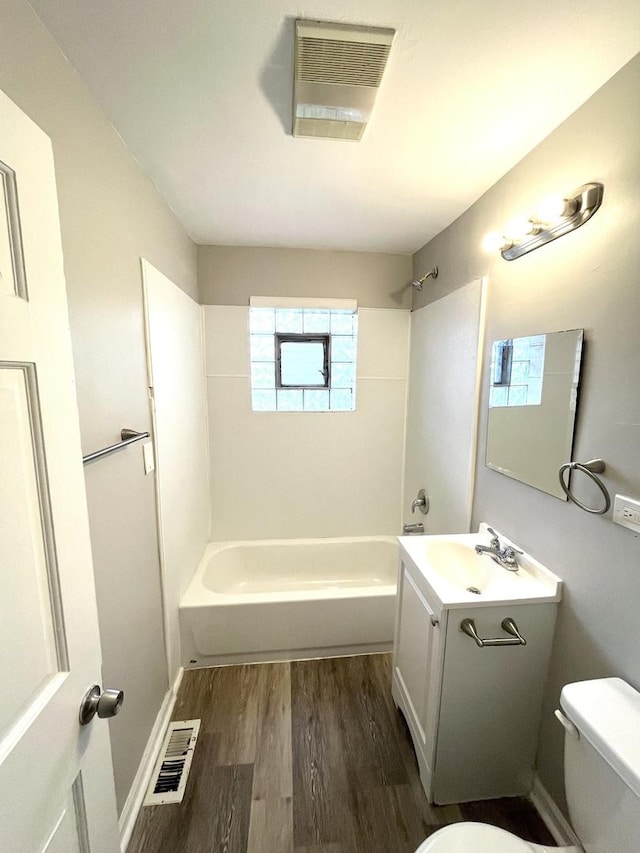 full bath with wood finished floors, toilet, washtub / shower combination, and vanity