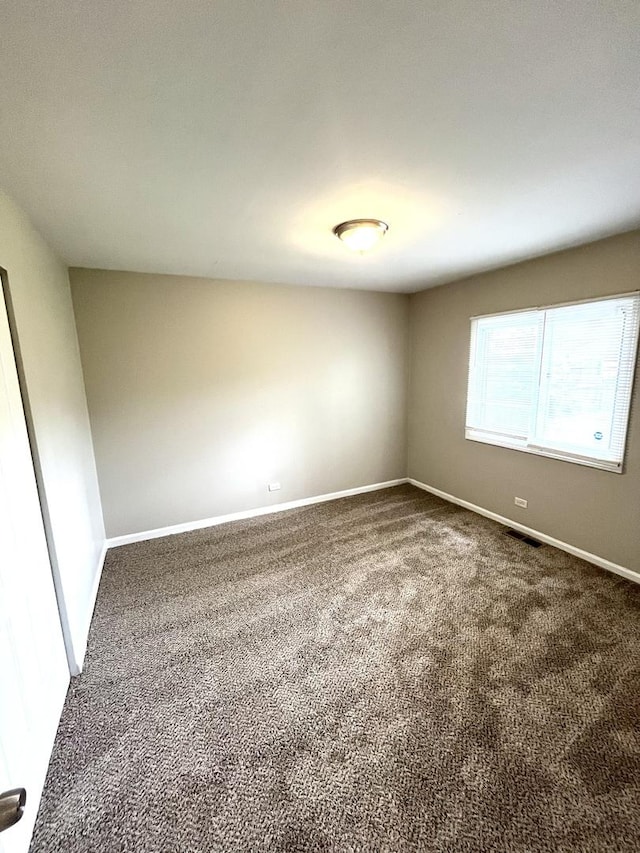 carpeted empty room featuring baseboards