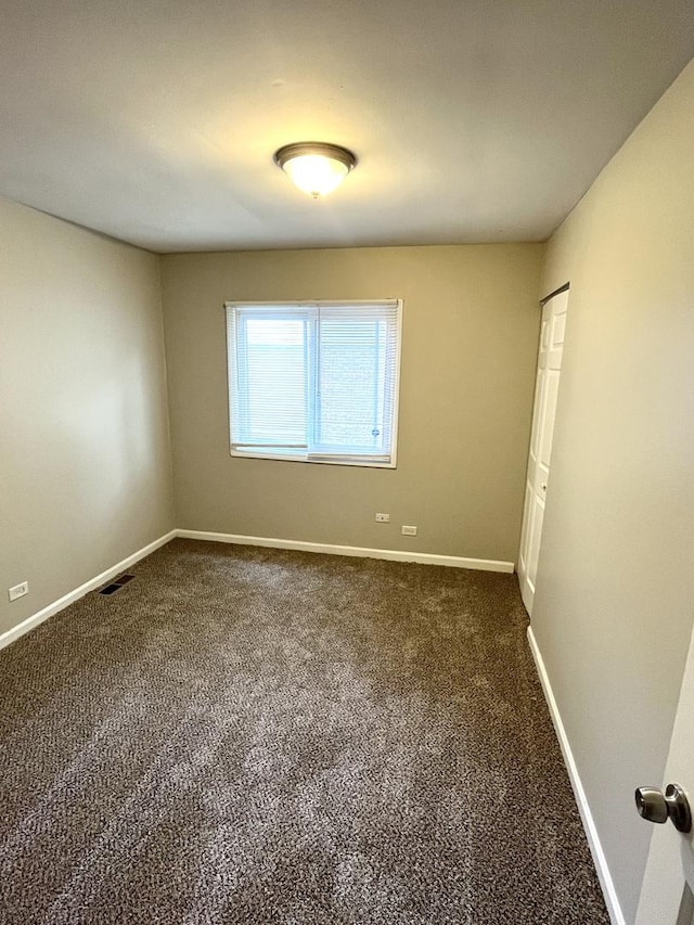 empty room featuring dark carpet and baseboards